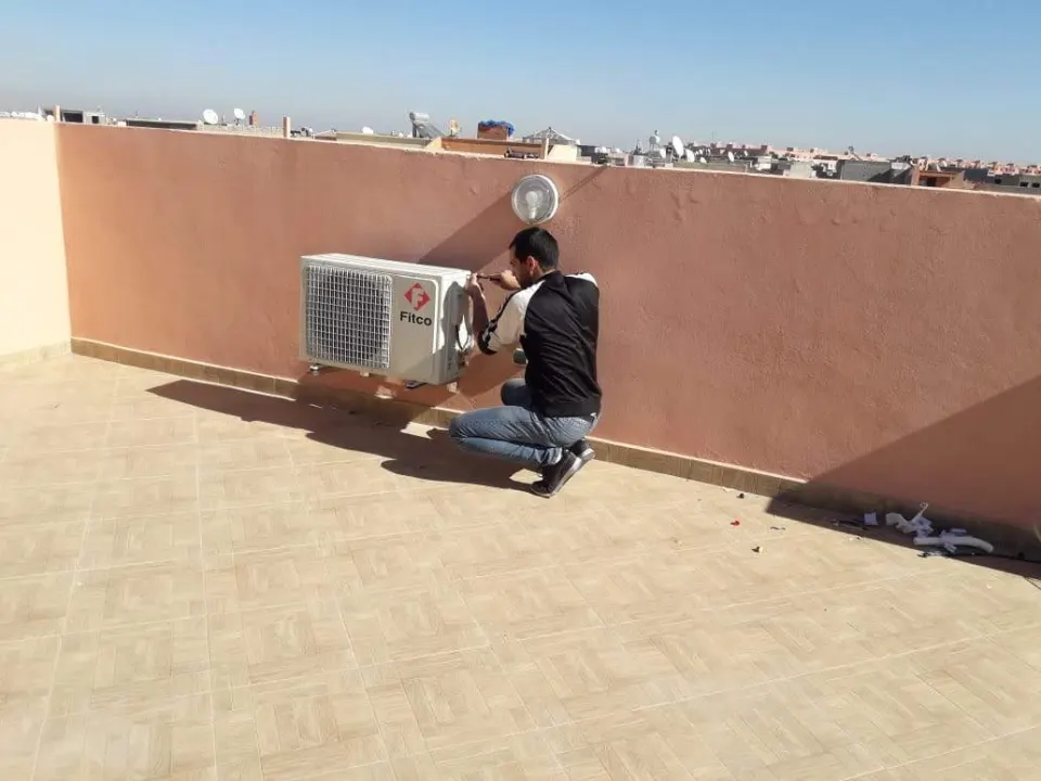Kabil Clim technician mounting an air conditioner outdoor unit on a rooftop terrace