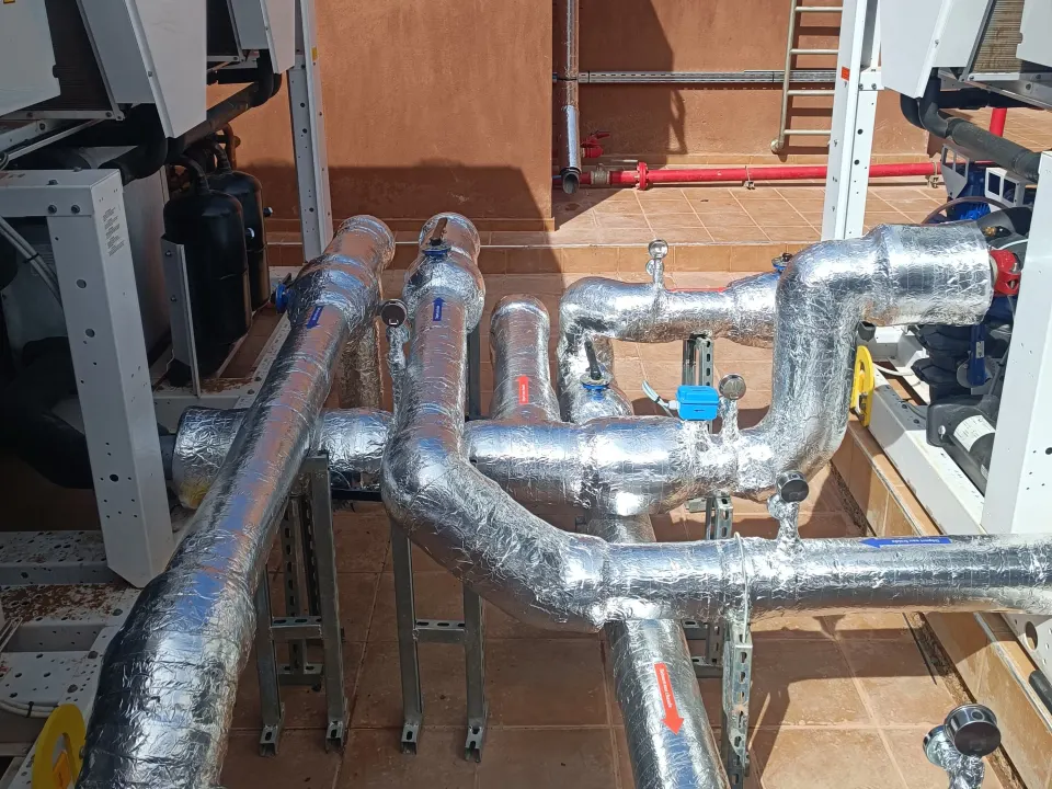 Insulated pipework connecting Aermec units on a rooftop