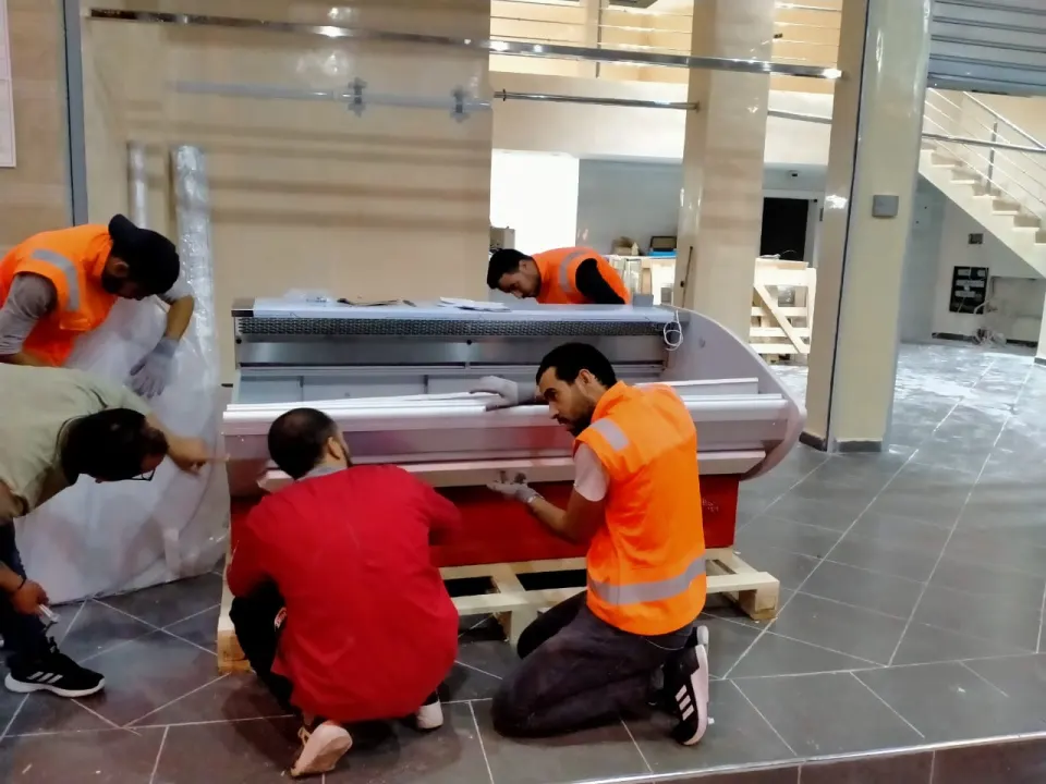 Techniciens installant une vitrine réfrigérée dans un commerce